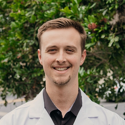 Chiropractor Austin Warren Smiling Outdoors In Lab Coat