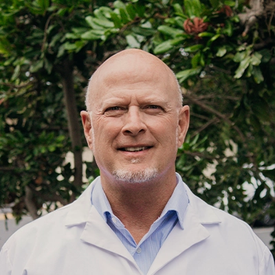 Chiropractor Daniel Warren Smiling Outdoors In Lab Coat